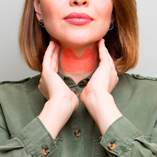 Mulher toca o pescoço, com ilustração destacando a glândula tireoide em vermelho sobre a pele, representando problema ou inflamação.